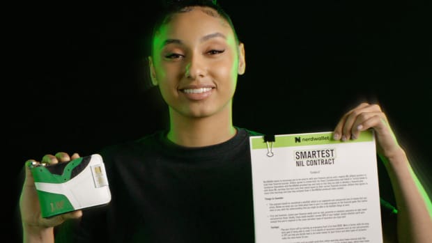 Juju Watkins holds up a contract and wallet in a photo shoot.